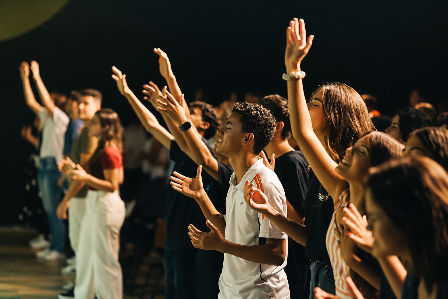 Jovens de mãos levantadas em um momento de louvor